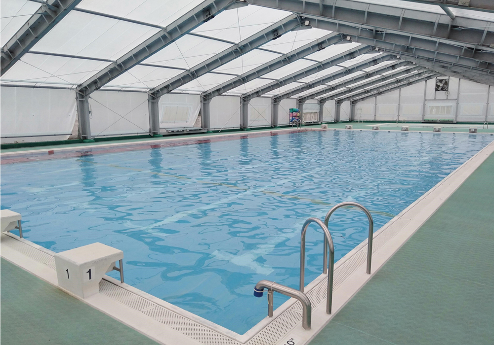 屋内にあるプールで、手前には飛び込み台やステンレス製の手すりが付いている長和町和田海洋センターの大プールの写真