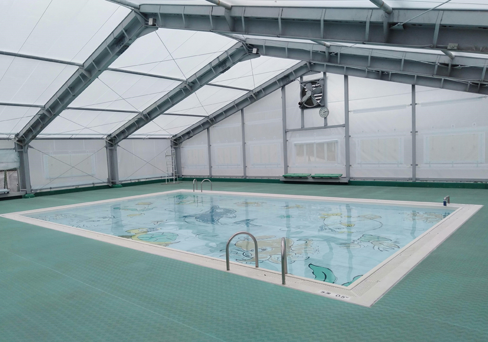 屋内にあるプールで、プールの底にイルカやカメなどのカラフルなイラストが描かれている長和町和田海洋センターの小プールの写真