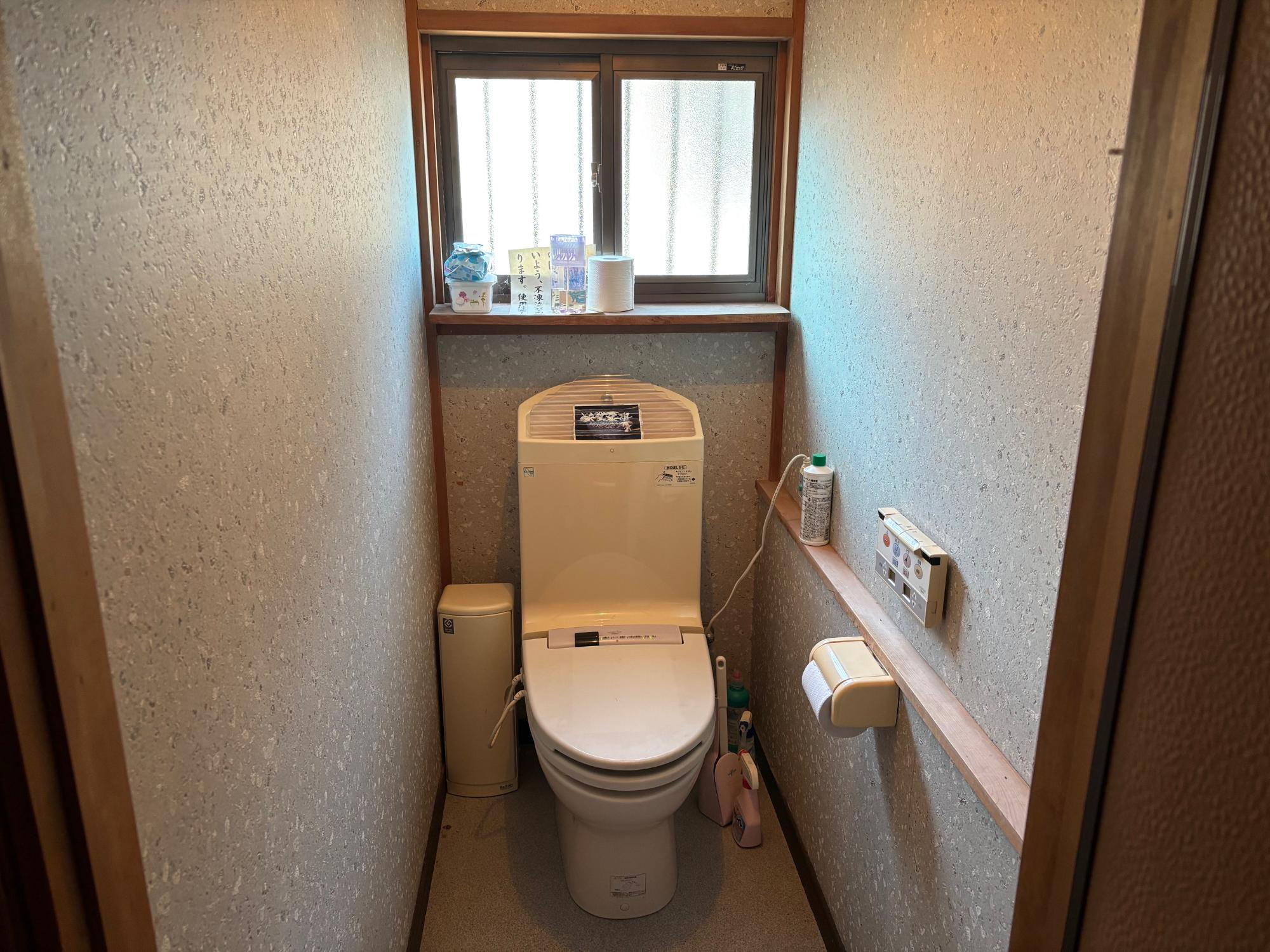 右側壁にトイレットペーパーホルダー、リモコン、正面奥上部に曇りアルミサッシ戸がある、洋式トイレの写真