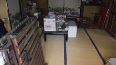 床には畳が敷かれ、ふすまも数枚あり、畳の上には黒いテーブル、その上に段ボールが置かれている1階和室の内観写真