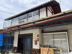 日本瓦屋根の白い建物で2階にはバルコニーがある木造2階建ての建物の外観写真