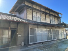 1階正面側には一面窓があり、2階にも大きな窓がある日本瓦屋根の木造2階建ての建物の外観写真