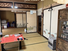 2つの和室が襖によって仕切られており、手前に戸棚とヒーターオレンジのテーブルが置かれた和室の写真