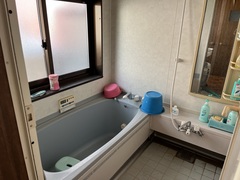 バスタブの両サイドにピンク色の洗面器と水色のバケツが置かれている様子の写真