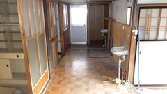 左側には部屋が2つ、奥には収納スペースのある部屋があり、右側の部屋の壁に手洗い場が設置されている廊下の写真