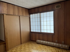 左奥に押入があり、右側には障子の窓、レトロな柄の床に丸まったカーペットが置かれている2階洋室の内観写真