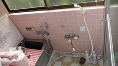 すりガラスの窓の下に正方形のピンク色のタイル壁がありそこにシャワーヘッドや蛇口が設置され、左にバスタブがある浴室の写真