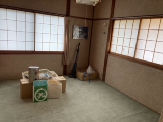 左側、右側に閉じた障子戸、カーペットの上に段ボール箱が重なっている和室の内観写真