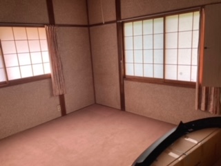 左側、右側に閉じた障子戸があり、カーペットを引いた右側手前に段ボールが置いてある、和室の内観写真