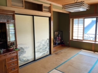 左側に仏壇、中央奥に押入れから紙、床の間、右側奥にサッシ、障子戸がある和室内観の写真