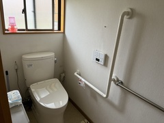 壁にはL字の手すりのついていて、洋式トイレが設置されているトイレの写真